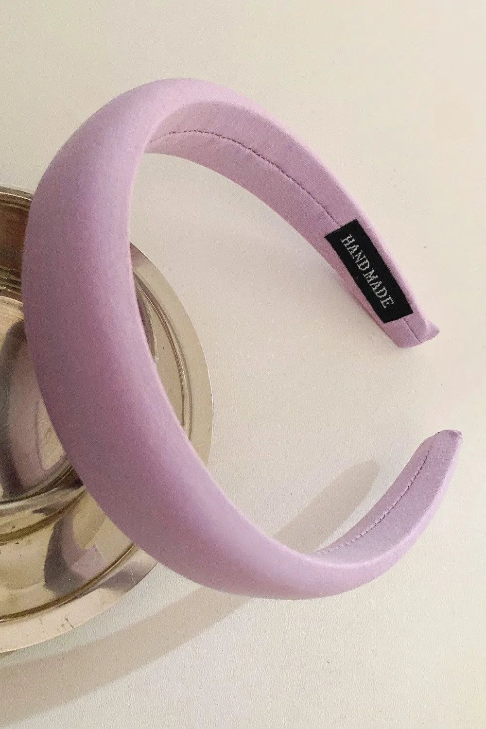 Lilac padded headband with textured fabric and a black "Handmade" tag.