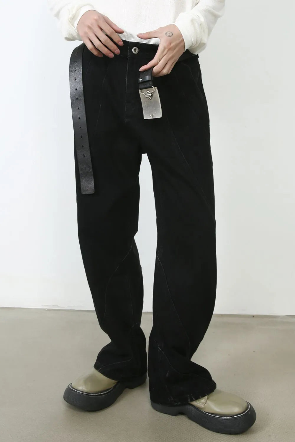 Dark denim trousers with sculpted seams and a black leather belt.