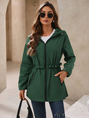 Dark green hooded windbreaker jacket with ruffled waistline and zip pockets.