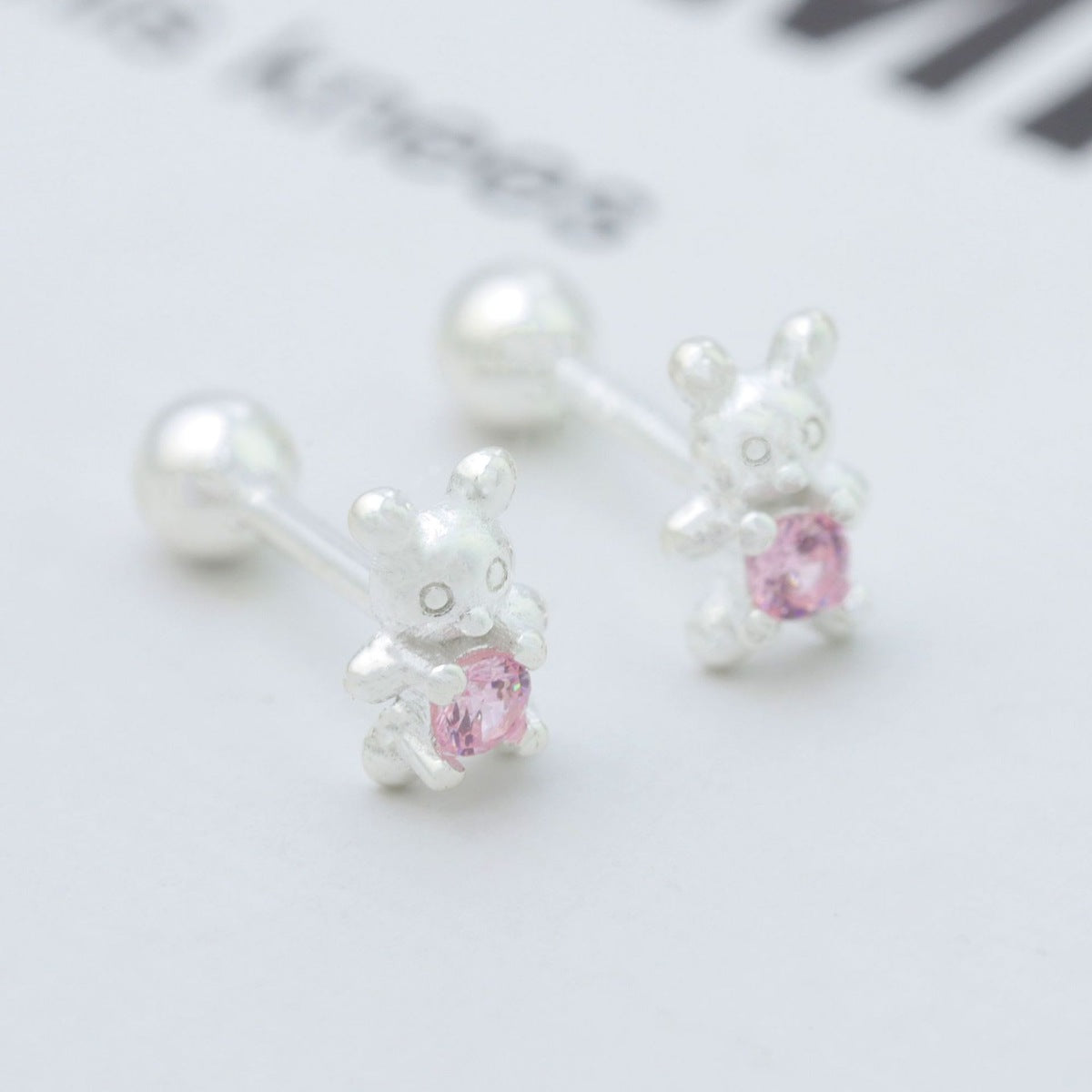 Silver bear stud earrings with pink zircon stone detail.