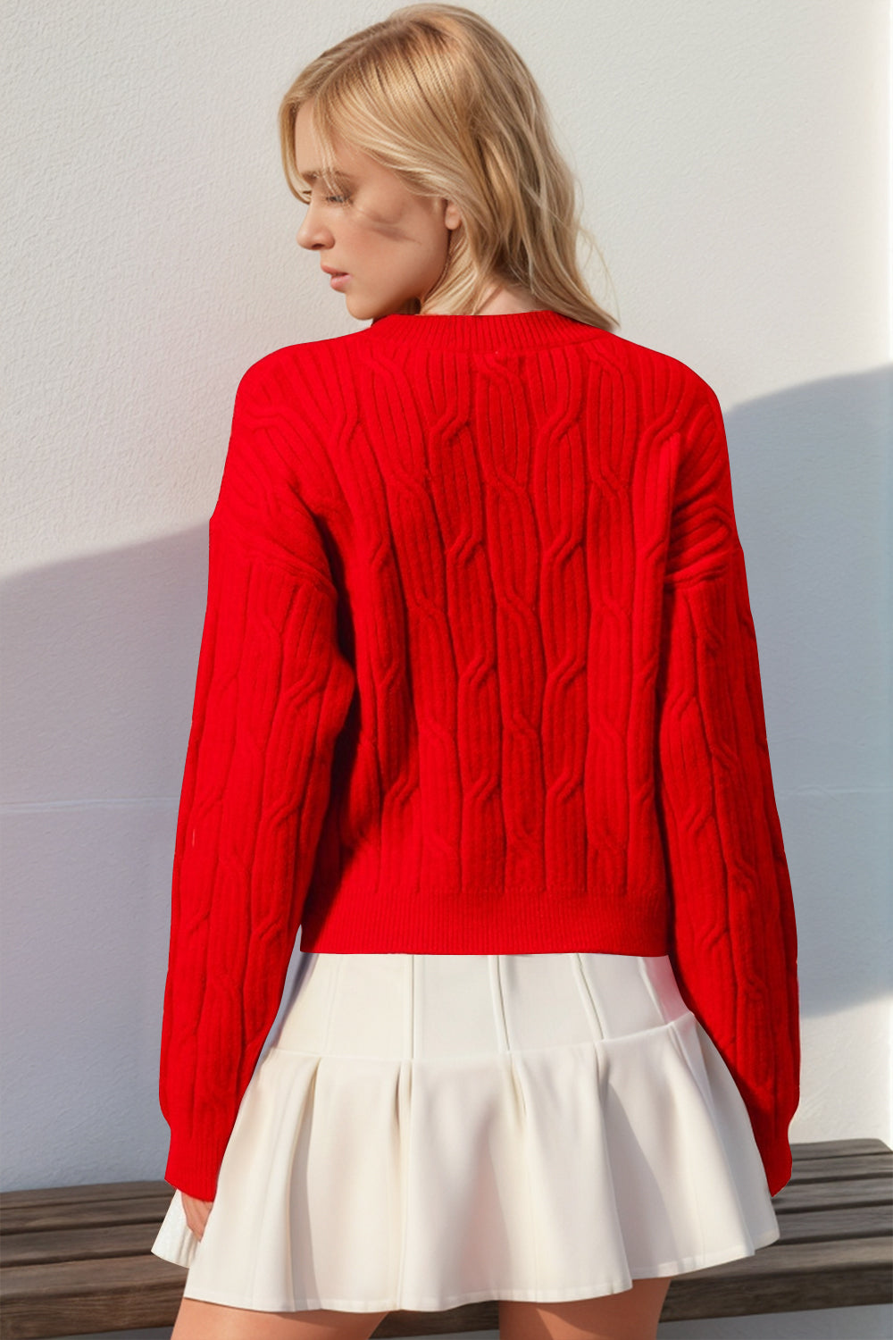 Red cable knit sweater with long sleeves and a crew neck, featuring a bow detail.
