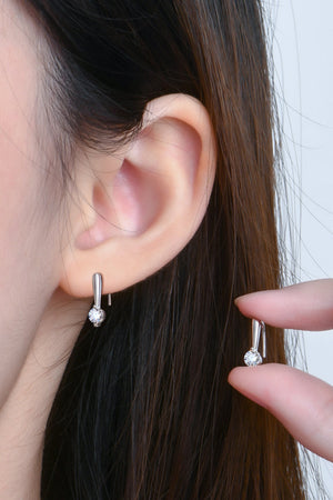 Silver moissanite hook earrings with minimalist sparkle shown on ear and held by fingers.