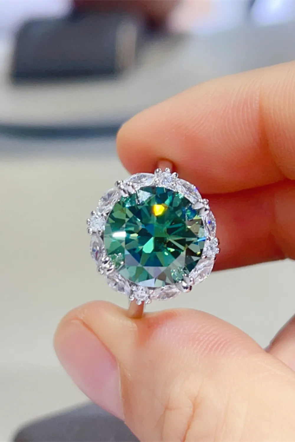 Emerald halo sterling silver cocktail ring with dark green center stone and clear accent stones.