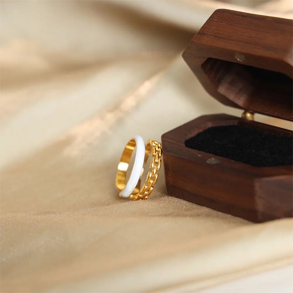 Gold chain link and white enamel open rings with a wooden box.