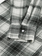 Button-up long sleeve cotton shirt in black and white plaid with a single button cuff detail.