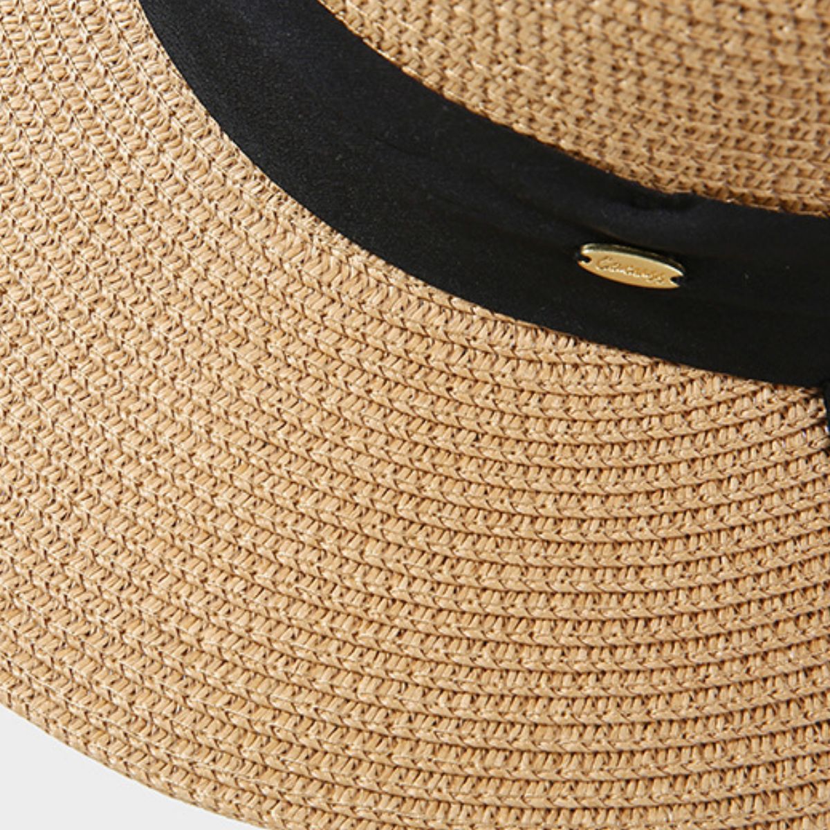 Woven straw sun hat in beige with black band and gold detail.