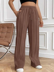 Brown pleated wide-leg lounge trousers with drawstring waist and pockets.