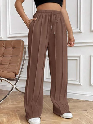 Brown pleated wide-leg lounge trousers with drawstring waist and pockets.