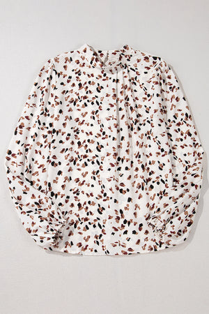 White high-neck blouse with abstract print and tie detail.