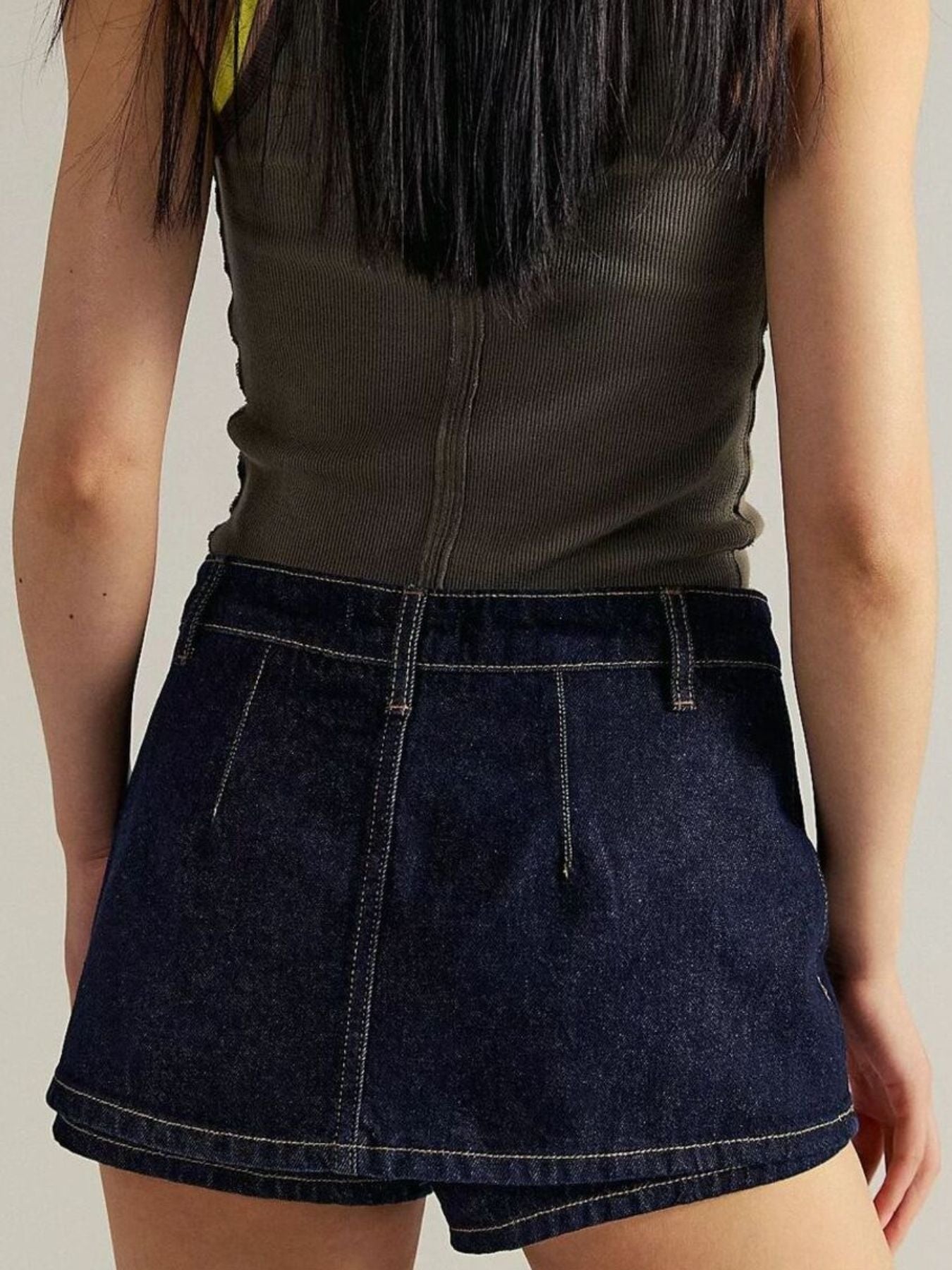 Dark blue denim mini skort with button closure and contrast stitching.