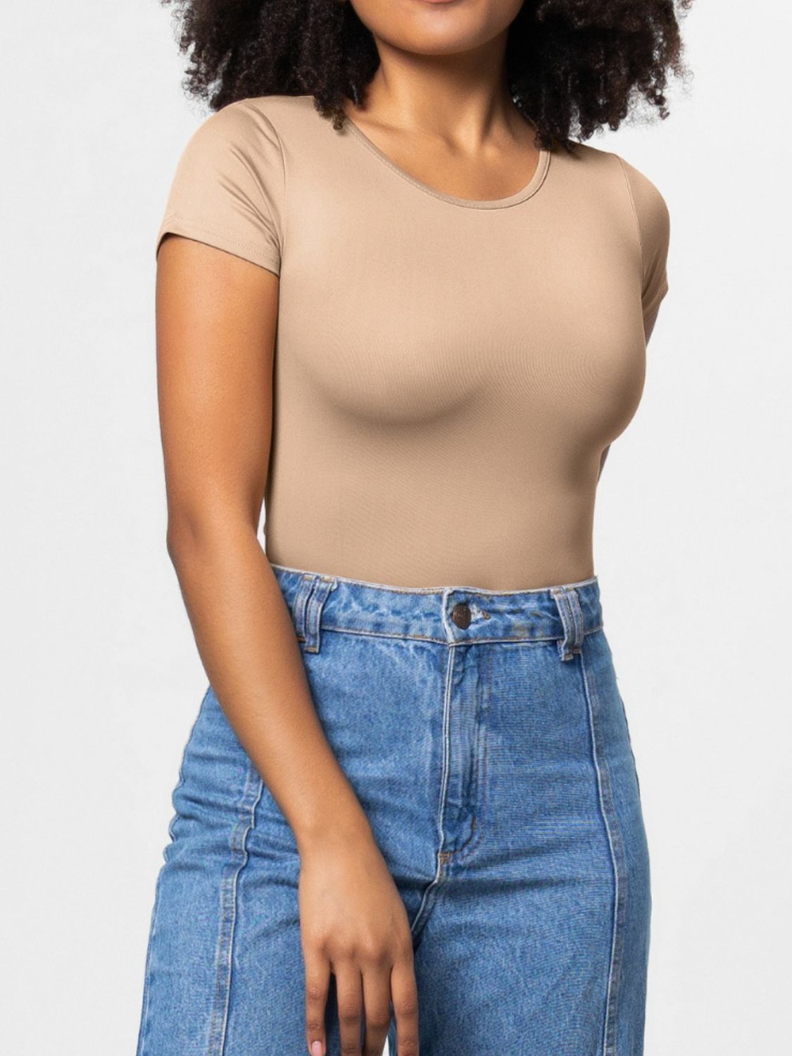 Tan scoop-neck bodysuit with short sleeves, styled with high-waisted jeans.