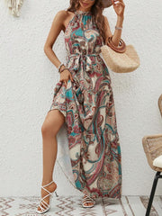 Halter neckline maxi dress with paisley print in brown, green, and pink, featuring a tie waist and tiered skirt.