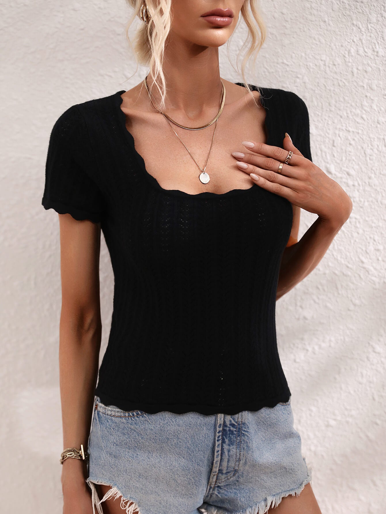 Black knit top with scalloped square neckline and short sleeves.