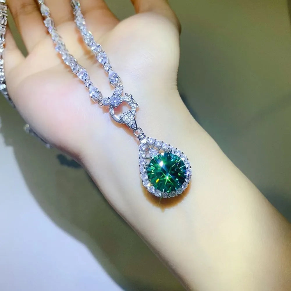 Silver moissanite halo pendant necklace with a large green pear-cut center stone.