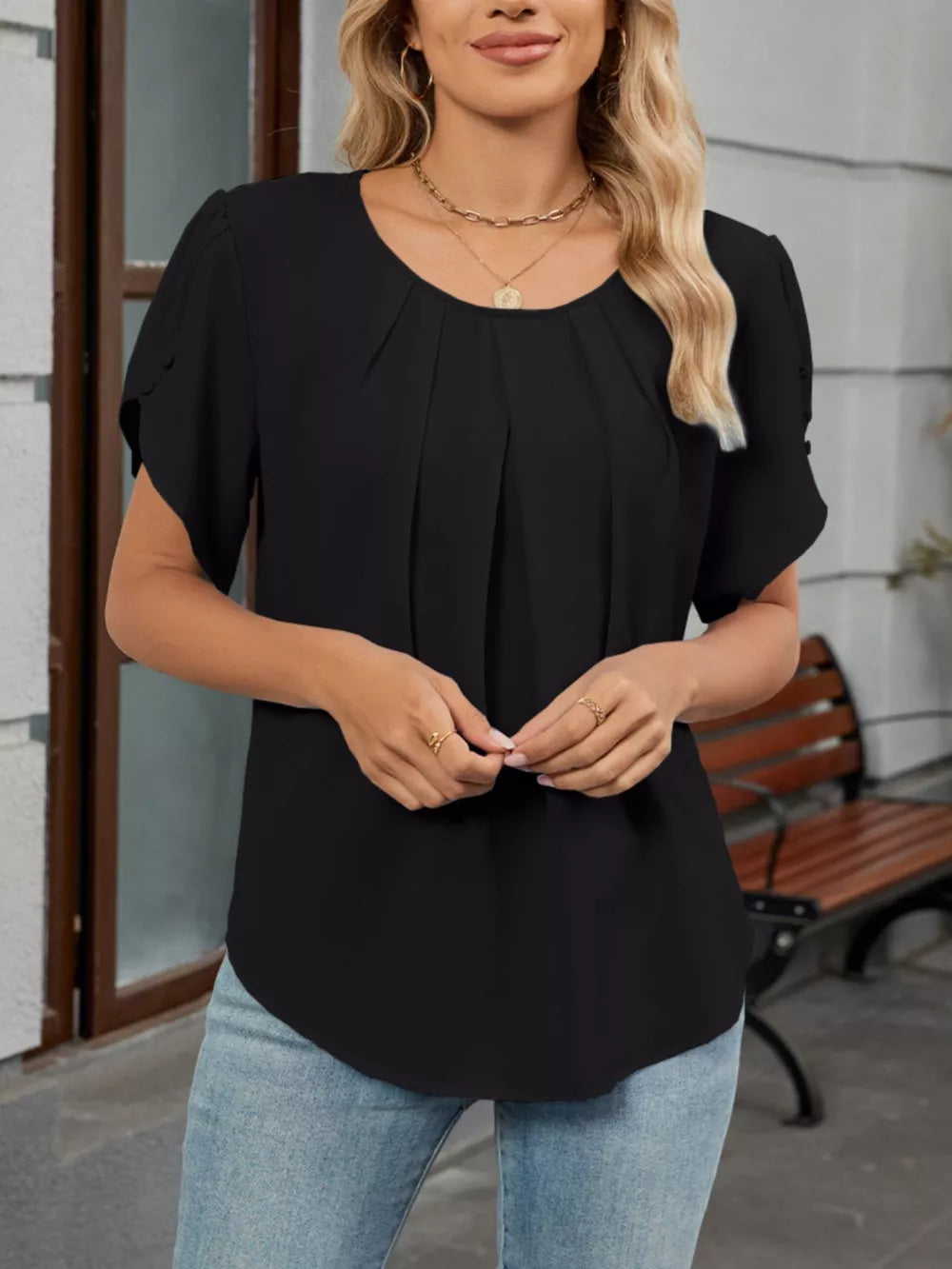 Black pleated short sleeve polyester blouse with round neckline.