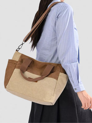 Multi-pocket canvas travel bag in taupe with adjustable strap and top handles.