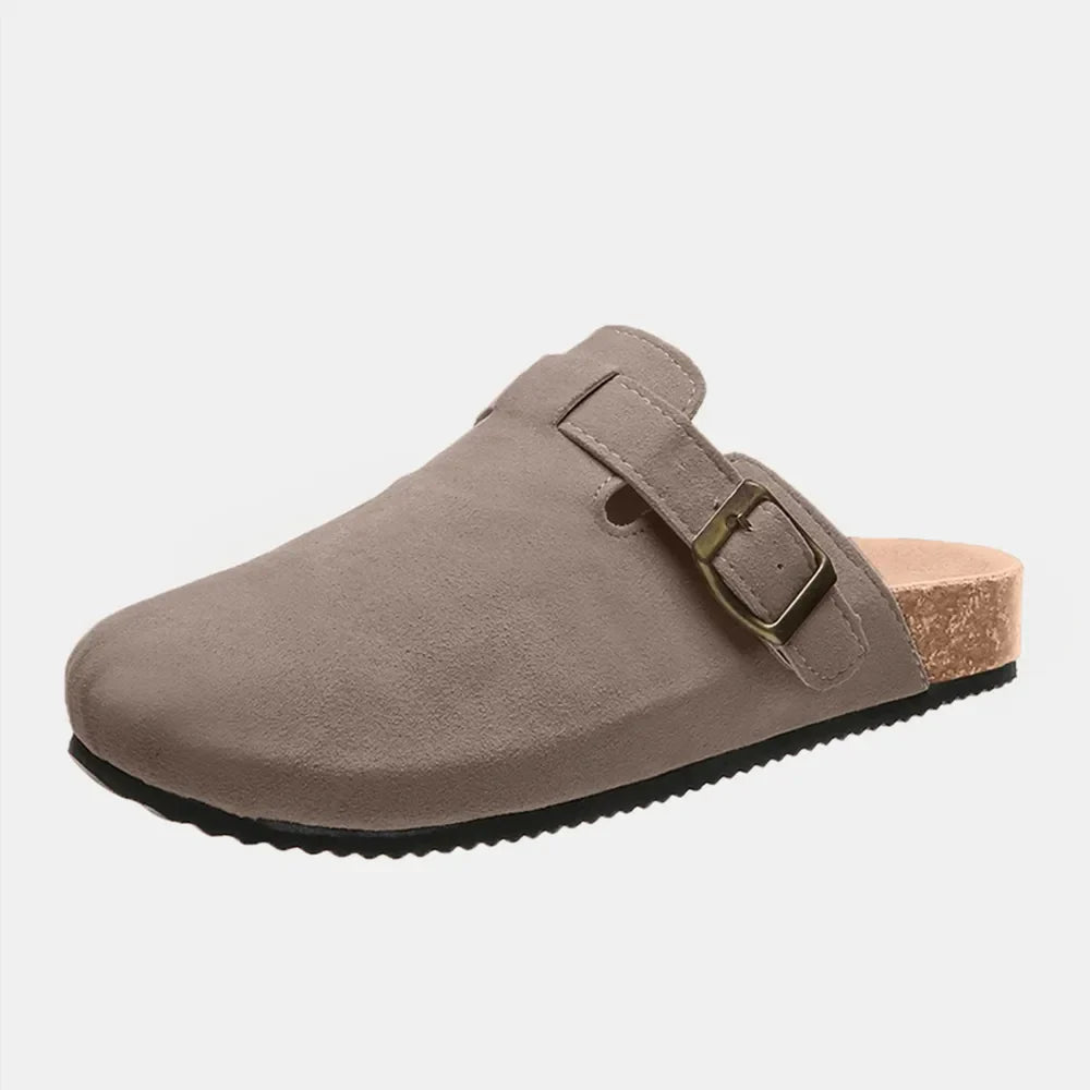 Suede clog slides in beige with cork sole and adjustable buckle detail.