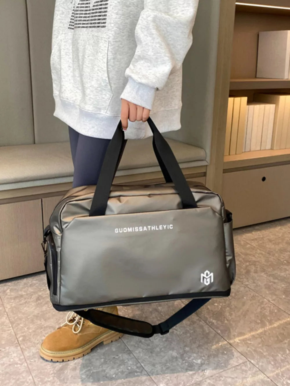 Premium Oxford cloth travel duffle bag in metallic grey with adjustable strap and logo detail.