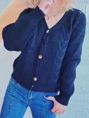Black cable knit raglan cardigan with v-neck and button front, styled with jeans.