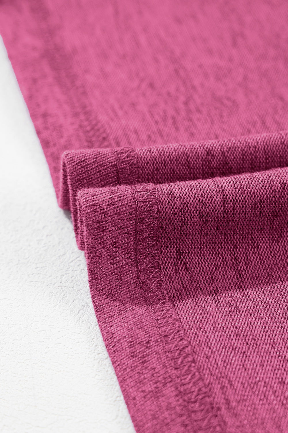 Hot pink ribbed tee with rolled cuff detail and visible stitching.