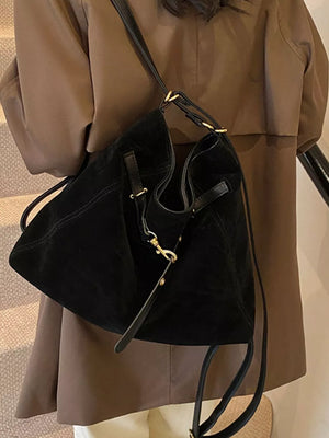 Black slouchy crossbody bag with gold hardware and adjustable strap.