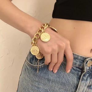 Chunky gold-plated coin charm bracelet with adjustable chain and detailed coin pendants.