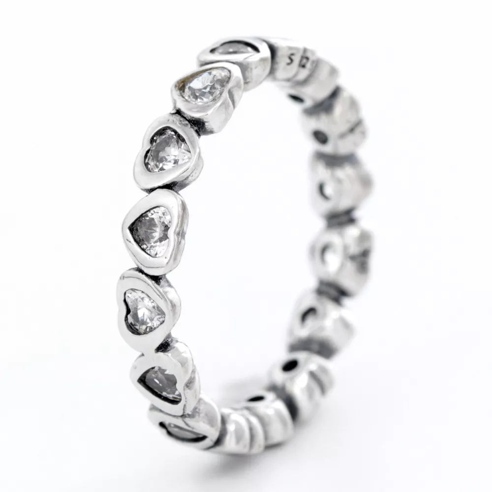Eternity ring in sterling silver with a band of small, clear heart-shaped cubic zirconia stones.