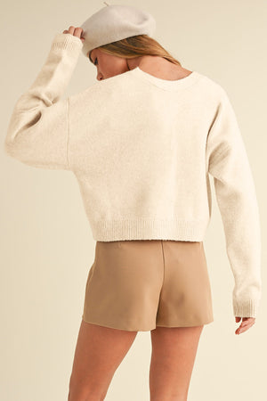 Ivory bouclé knit cardigan with crew neck and relaxed fit.