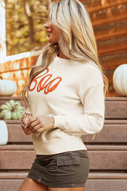 Ivory crewneck sweater with orange "Boo" appliqué detail.