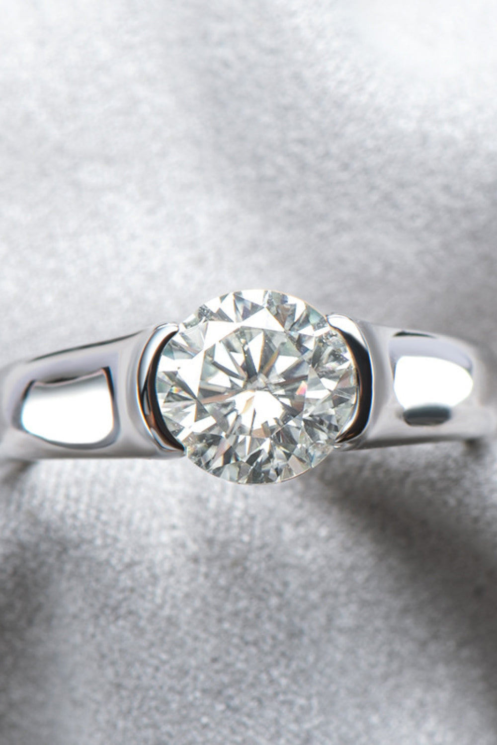 Platinum ring with a bezel-set round moissanite solitaire diamond.