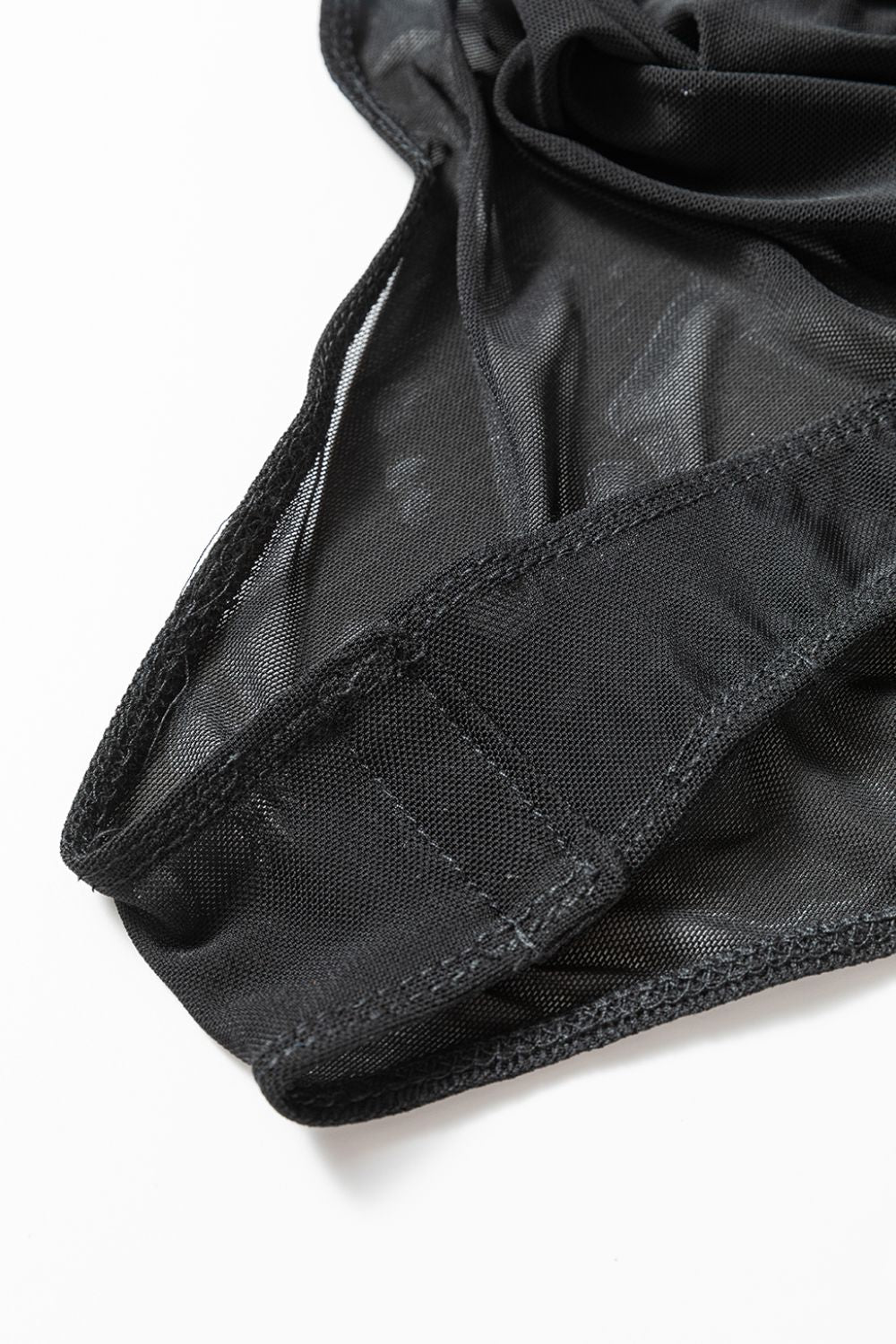 Black sheer mesh bodysuit detail with elasticized leg openings and stitched seams.