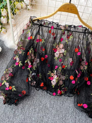 Black off-shoulder t-shirt with colorful floral embroidery and ruffled neckline.
