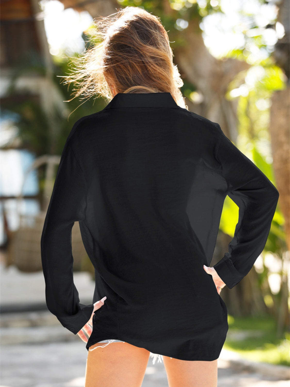 Black oversized linen beach shirt with long sleeves and collar, worn open over shorts.