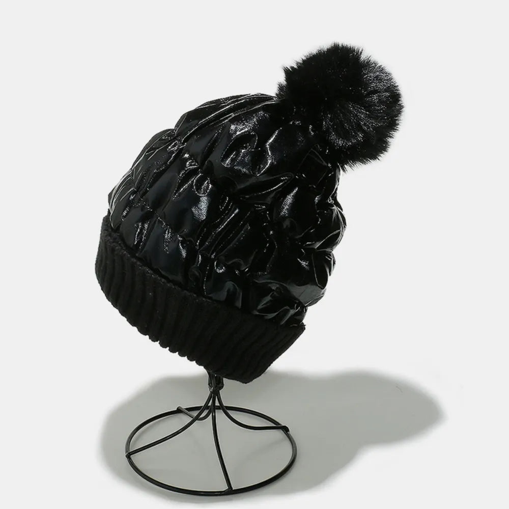 Black metallic padded beanie with quilted detail and faux fur pom.