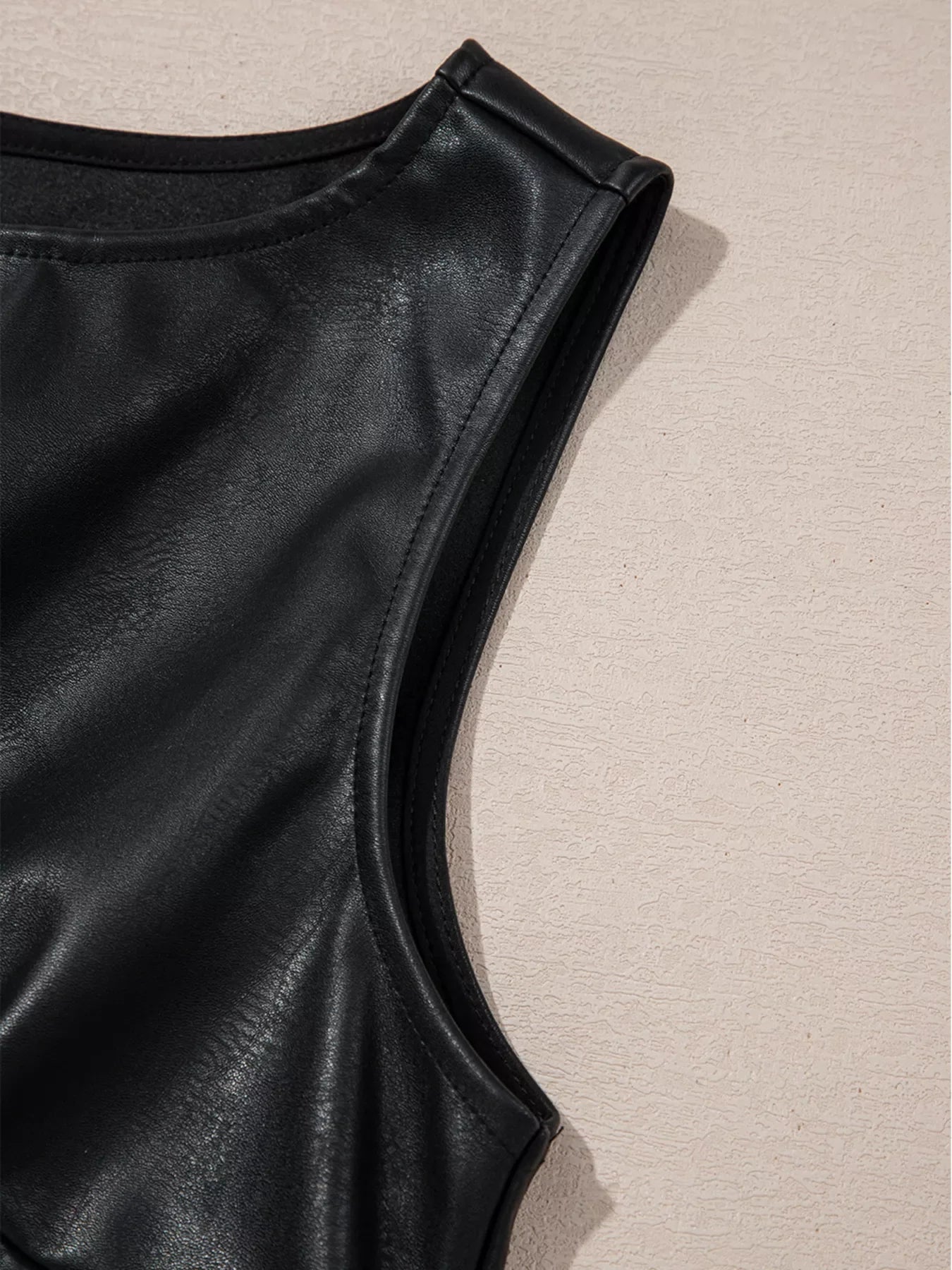 Black vegan leather sleeveless mini dress with a round neckline and clean seams.