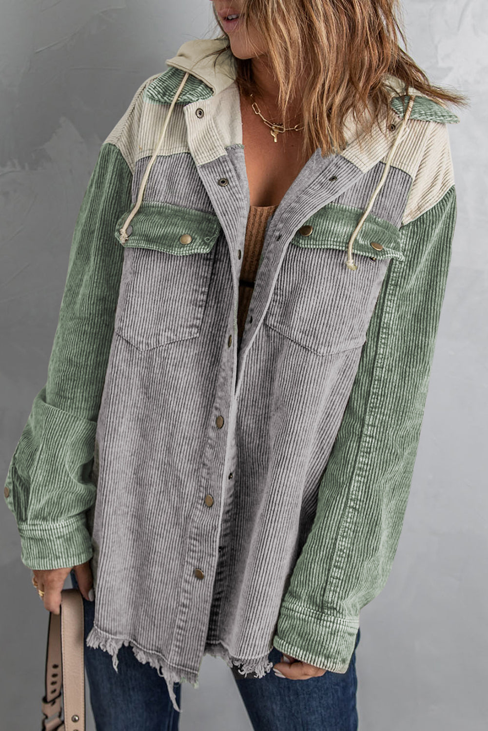Colorblock corduroy hooded utility jacket with green and gray panels and frayed hem.