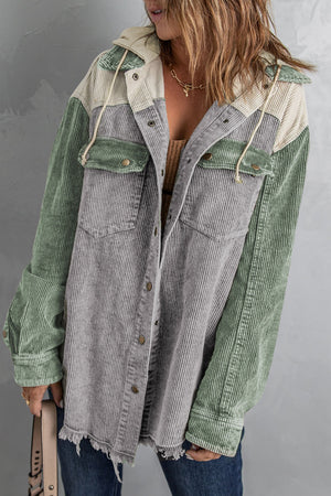 Colorblock corduroy hooded utility jacket with green and gray panels and frayed hem.