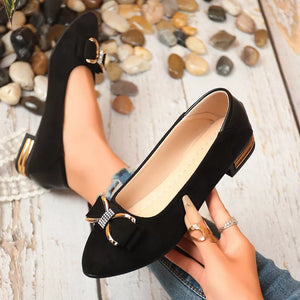 Black pointed-toe block heels with bow detail and gold heel accent