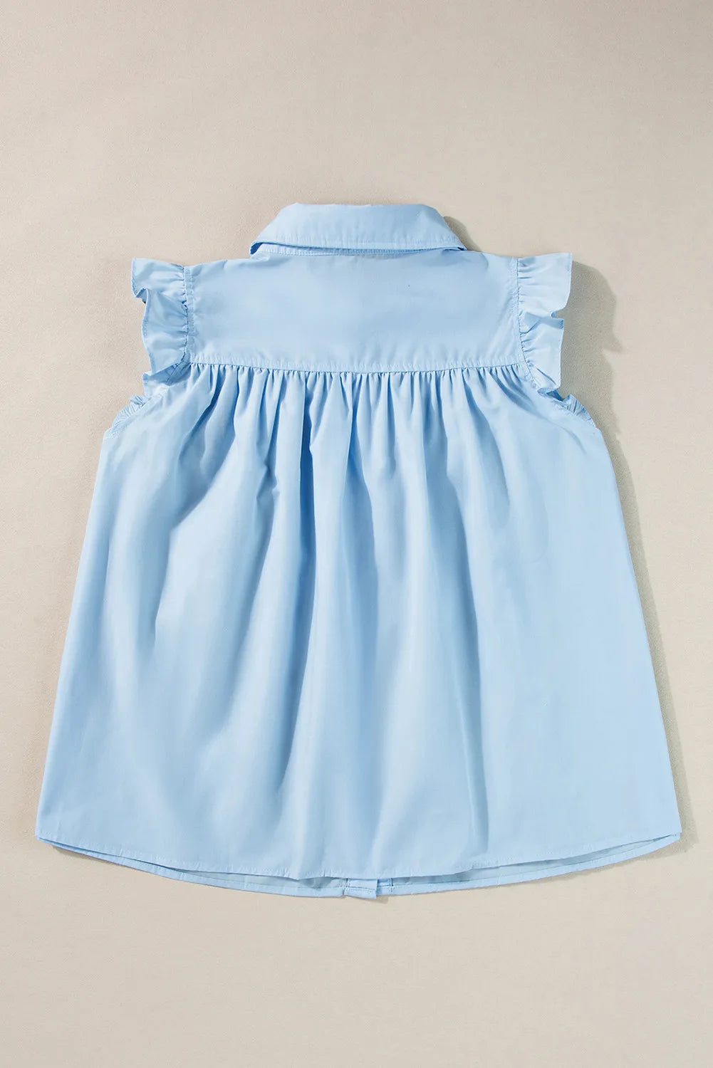 Light blue poplin ruffled yoke sleeveless blouse with gathered detail.