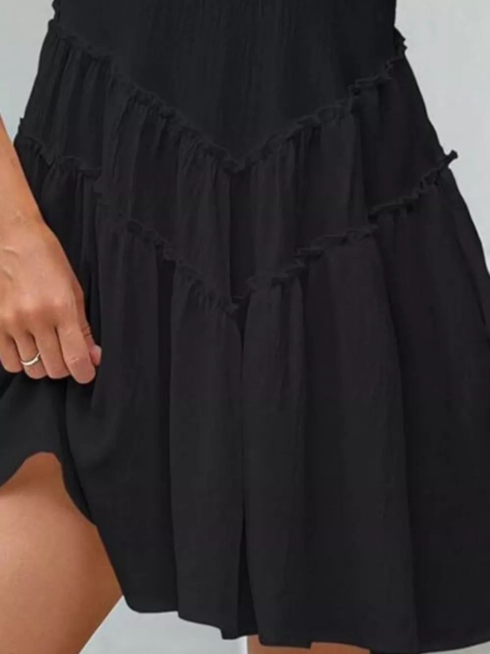 Black frill tiered mini dress with a V-shaped ruffle detail.