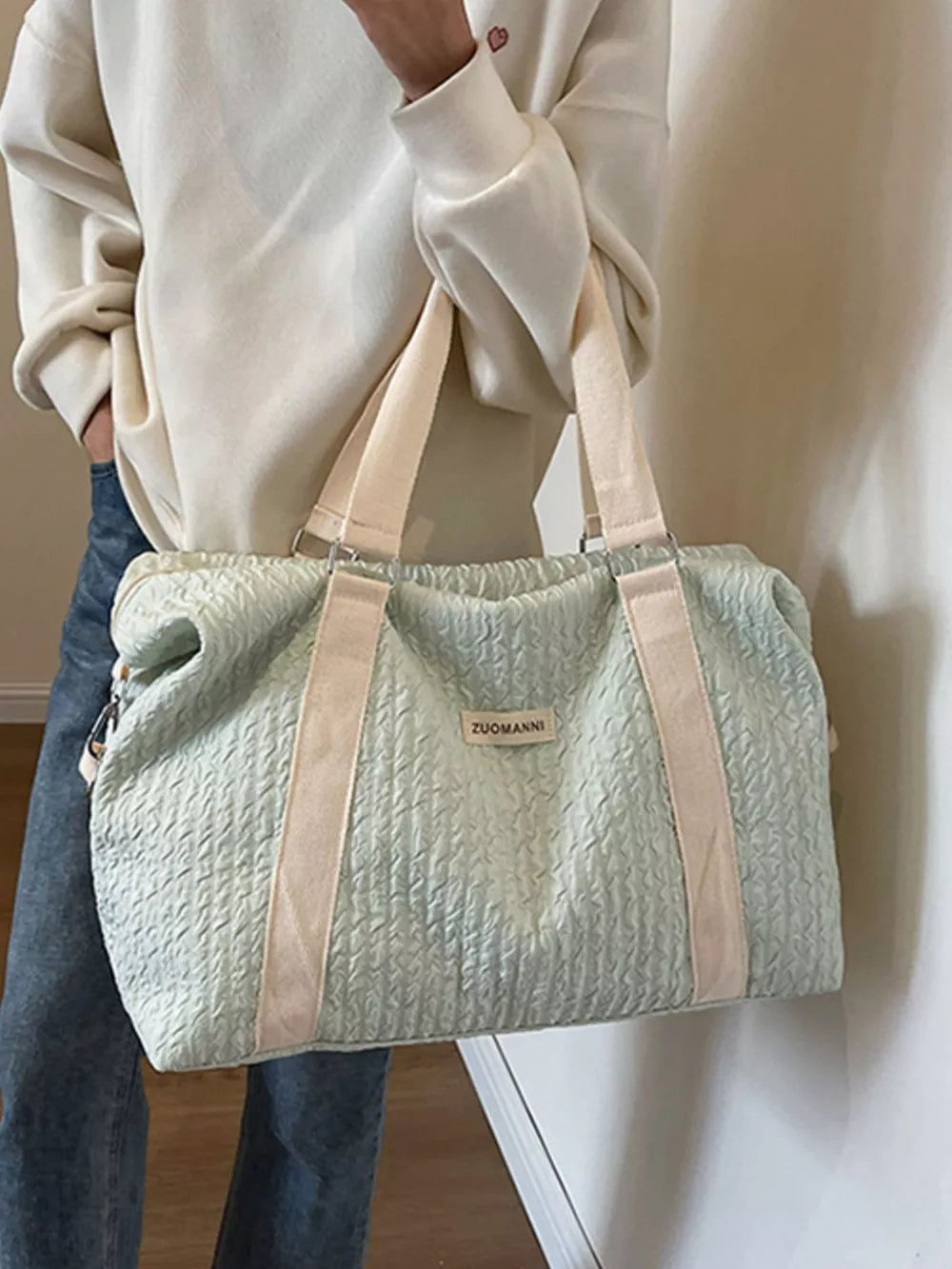 Light blue textured travel bag with cream straps and a detachable pouch.