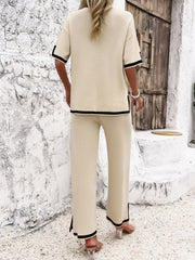 Cream knit co-ord set with contrast black trim on short sleeves and wide leg pants with side slits.