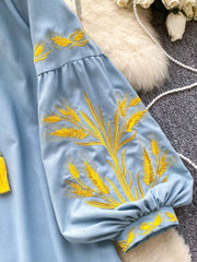 Blue embroidered tie-neck blouse with puff sleeves and wheat detail.
