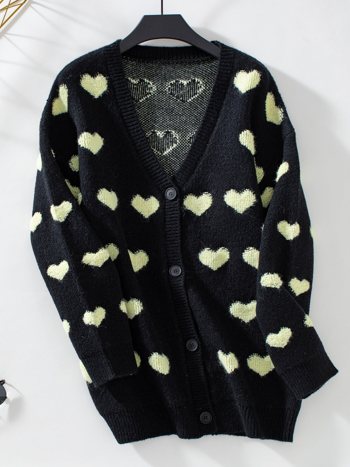 Black acrylic knit cardigan with allover light yellow hearts and button front.