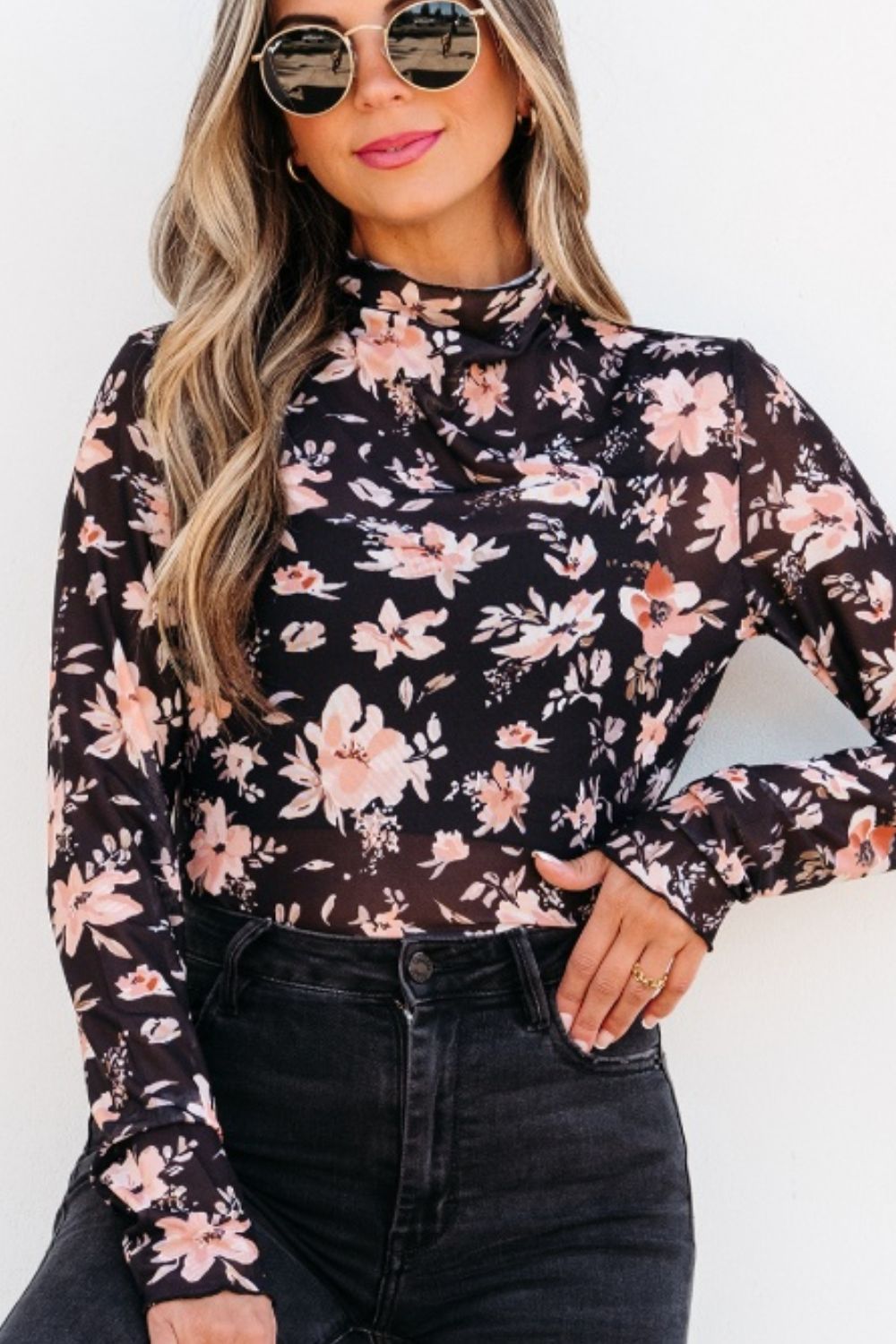 Sheer black floral mock neck blouse with long sleeves.