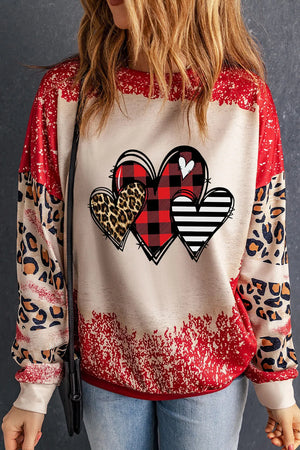 Sweatshirt with heart graphic patchwork, buffalo plaid, leopard print, and stripes on sleeves.