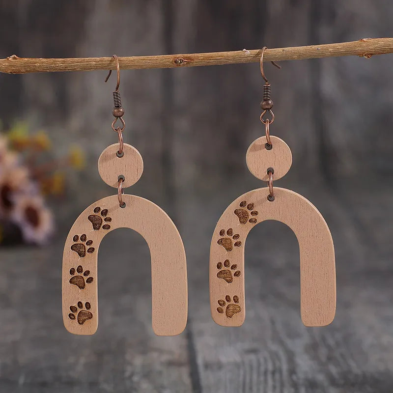 Wooden arch earrings in camel with engraved paw prints and copper hooks