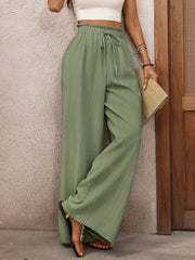 Crinkled wide-leg maternity pants in sage green with drawstring waist and scalloped hem.