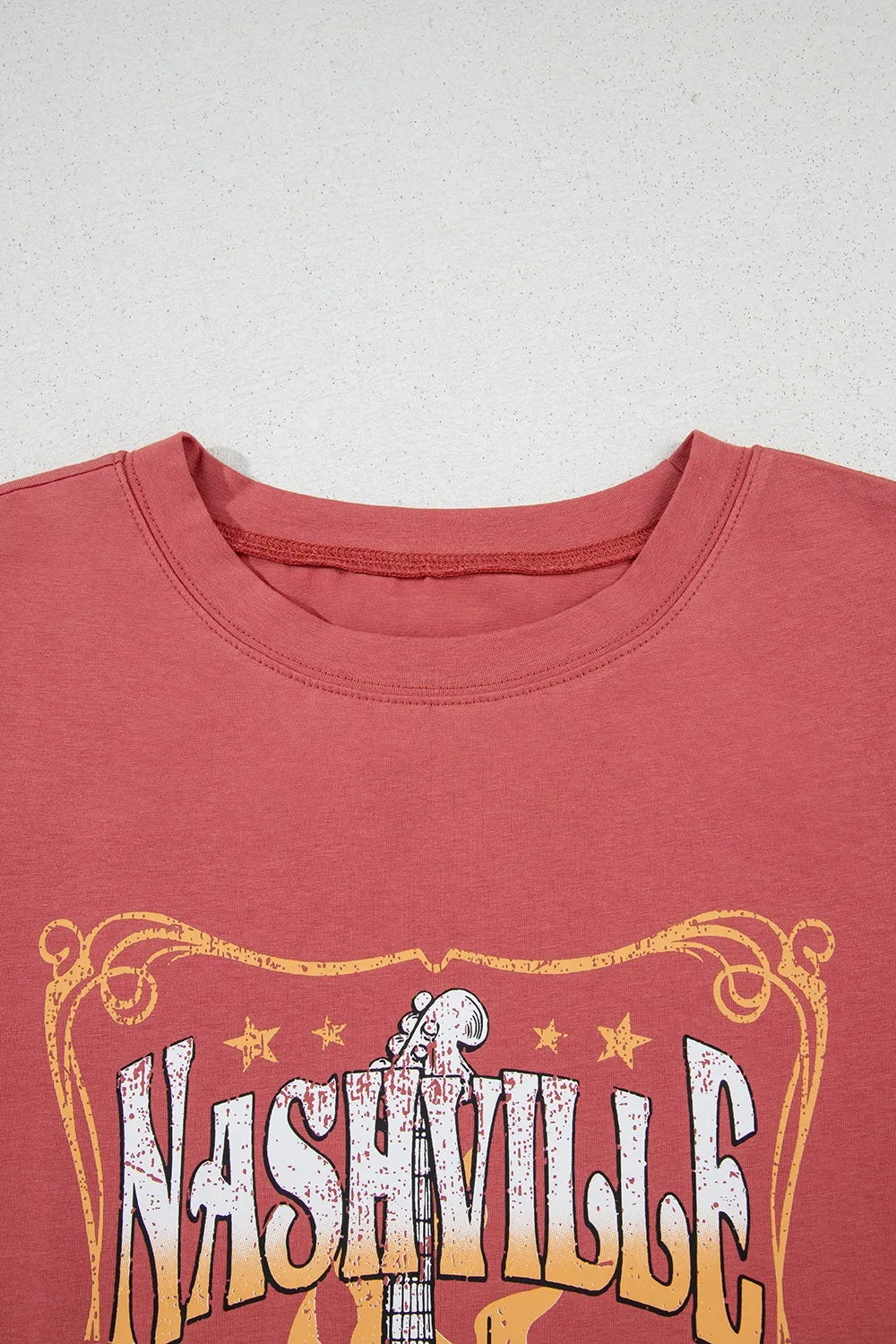 Burnt coral t-shirt with distressed Nashville graphic and guitar neck detail.