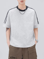 Light gray oversized casual t-shirt with black contrast stitching stripes on raglan sleeves.
